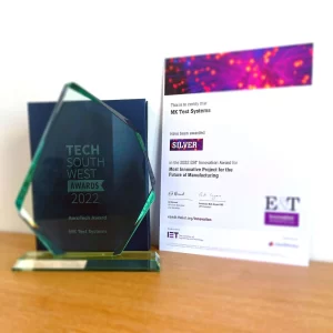 Image showing two awards presented to MK Test Systems for RTS. The award on the left is an angular glass trophy with an engraving of the words Tech South West Awards 2022 AeroTech Award MK Test Systems. To the right of this award is a Silver certificate awarded to MK Test Systems for the category of Most Innovative Project for the Future of Manufacturing in the 2022 E&T Innovation Awards.